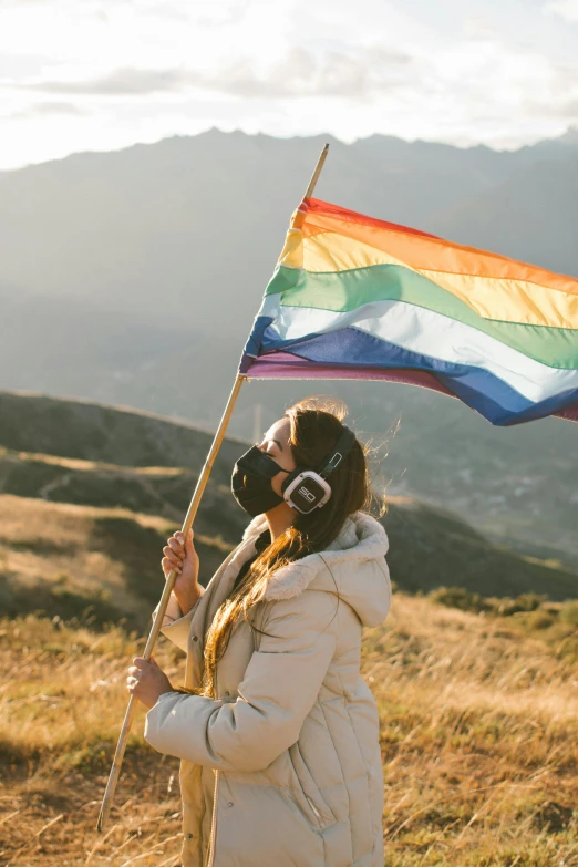 a woman holding a large flag and drinking a  beverage