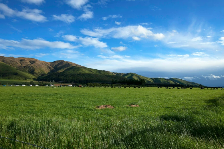 some clouds some green grass and some hills