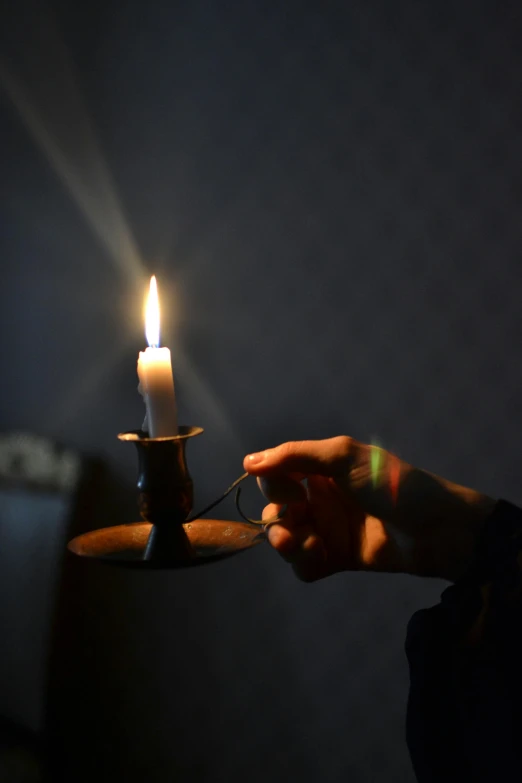 a candle is lit in the dark, while a candle holder stands upright