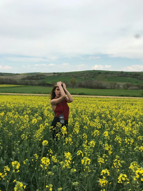 a woman stands in a field of yellow flowers