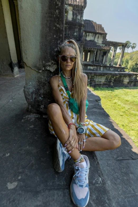 a woman sits on the ground wearing some sneakers