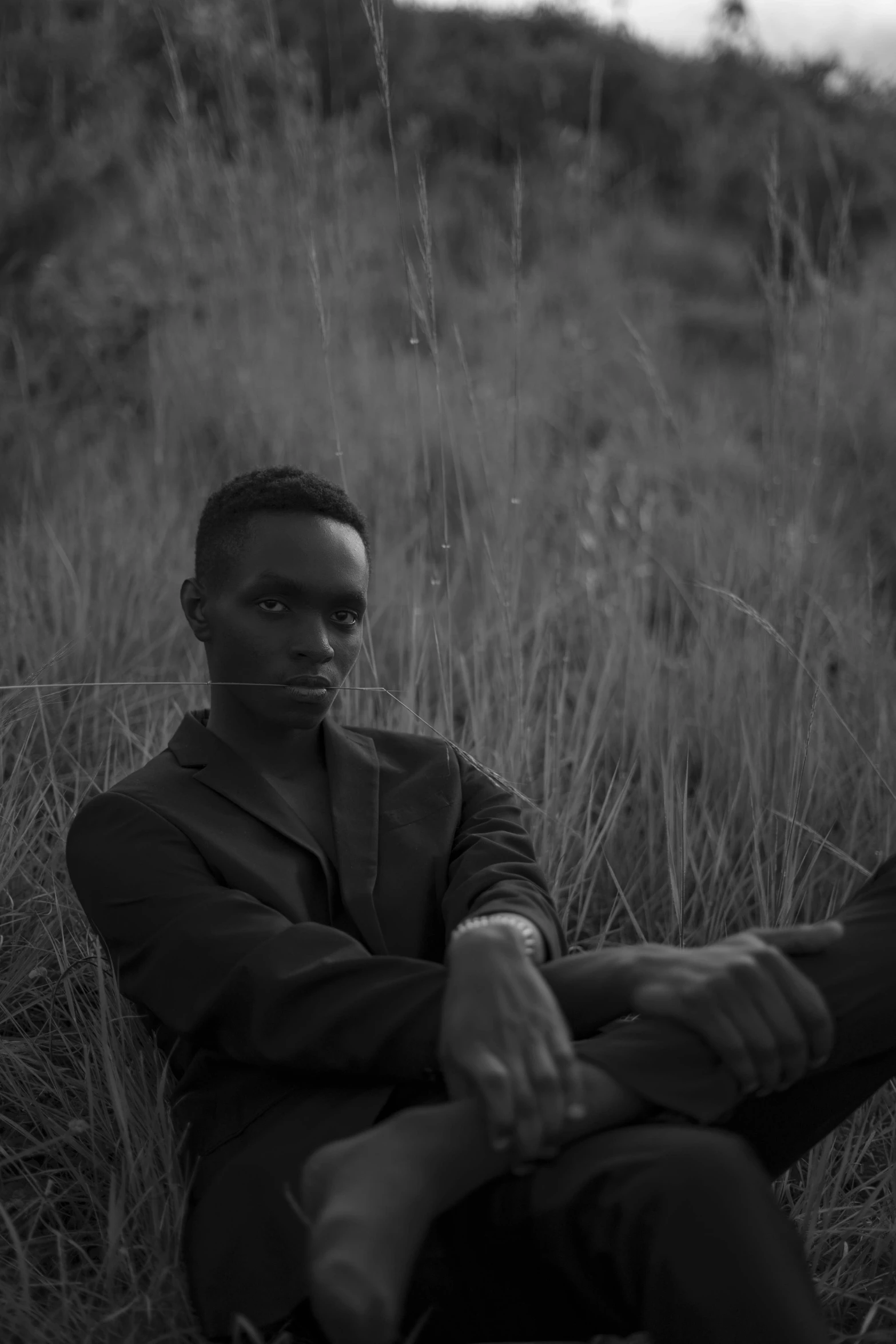 a man sitting on top of a grass covered field