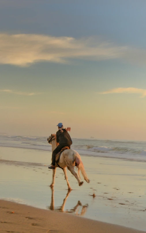 two people riding horses down the beach