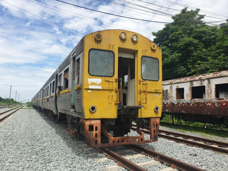 a yellow train traveling down tracks next to trees