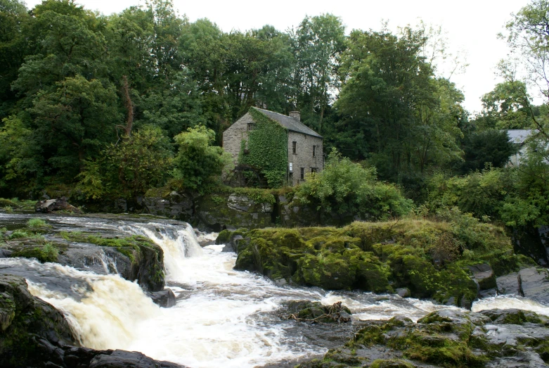 an old stone building overlooks a waterfall