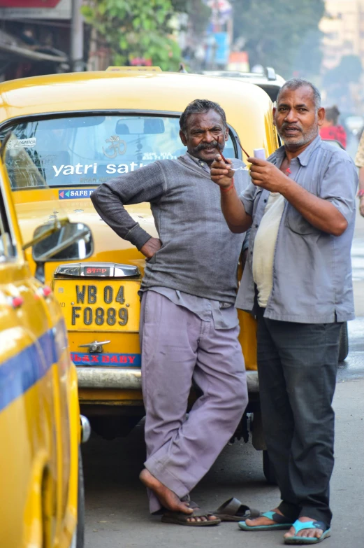 two men stand in front of a parked taxi