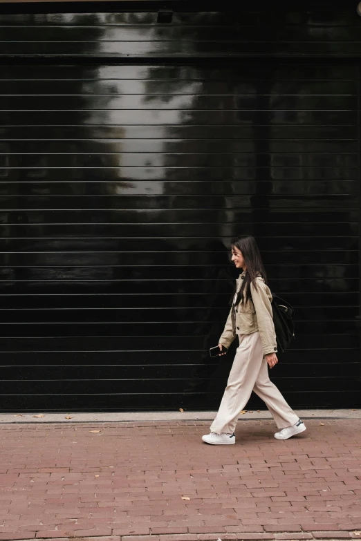 a woman walks down the sidewalk in front of a garage door