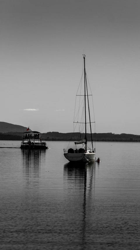 three boats sailing in the ocean, one with a long sail