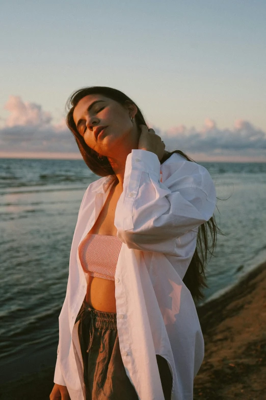 a woman in white jacket standing near water