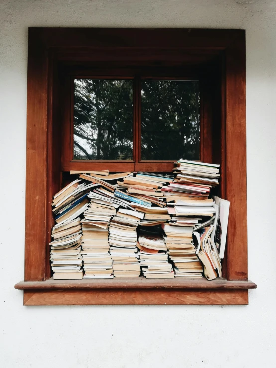 large stack of books stacked in window frame