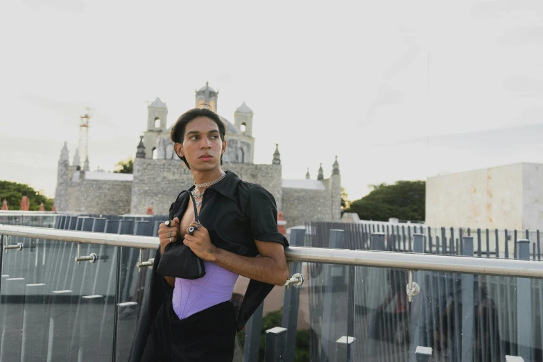 a man standing near a fence with some buildings