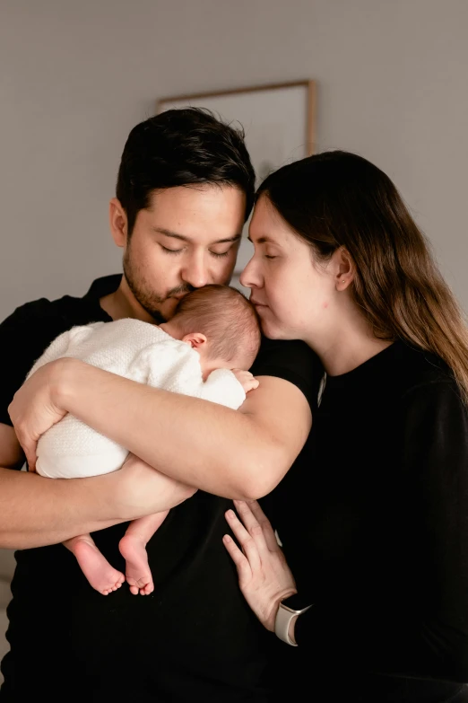 a man and woman standing in a room cuddling their baby