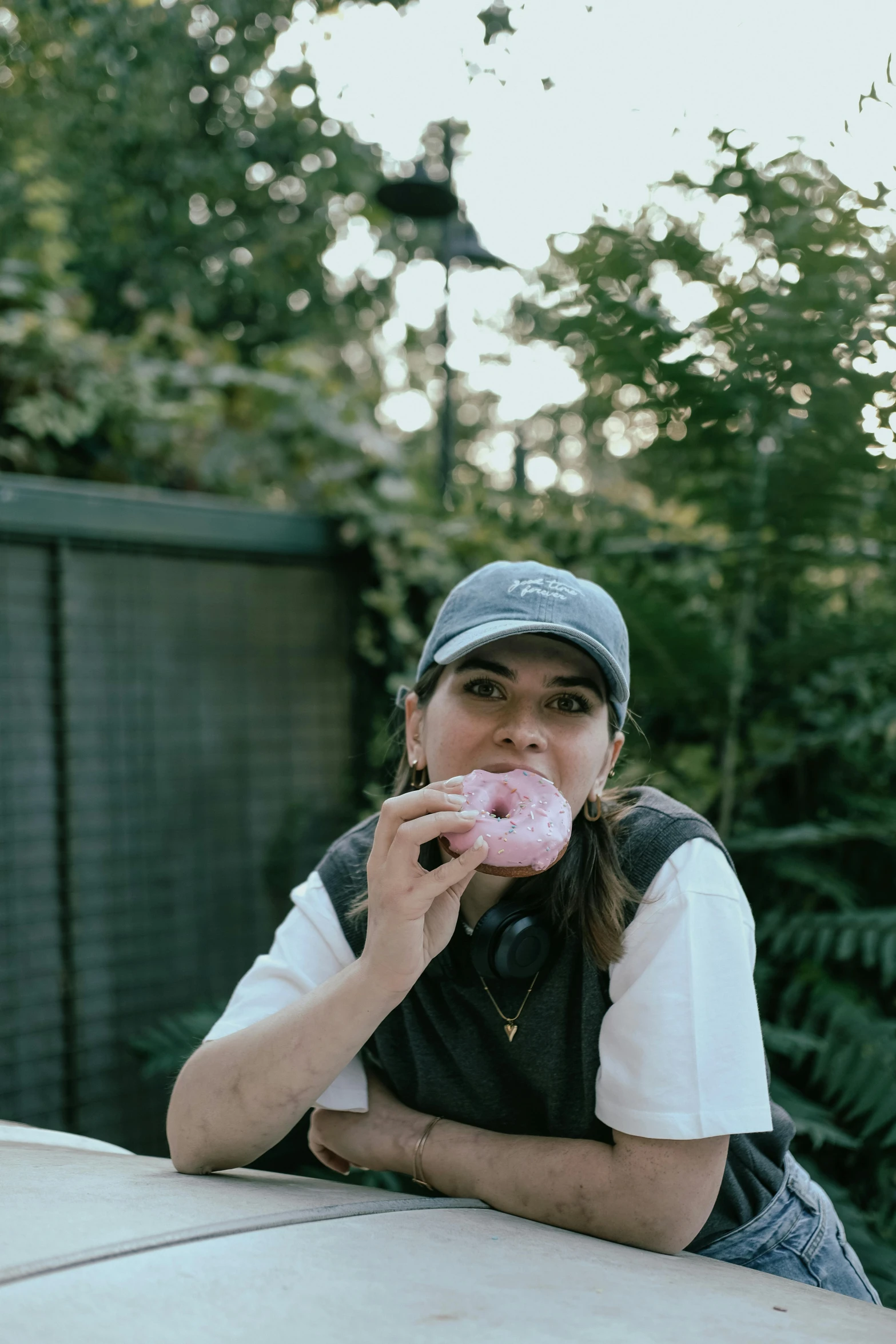 the young lady is eating a pink doughnut