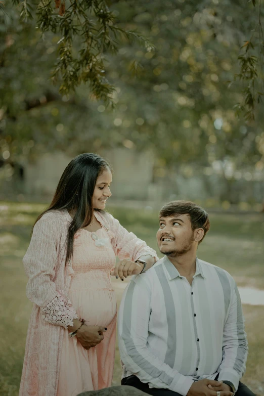 a pregnant couple smiling as they pose for a po