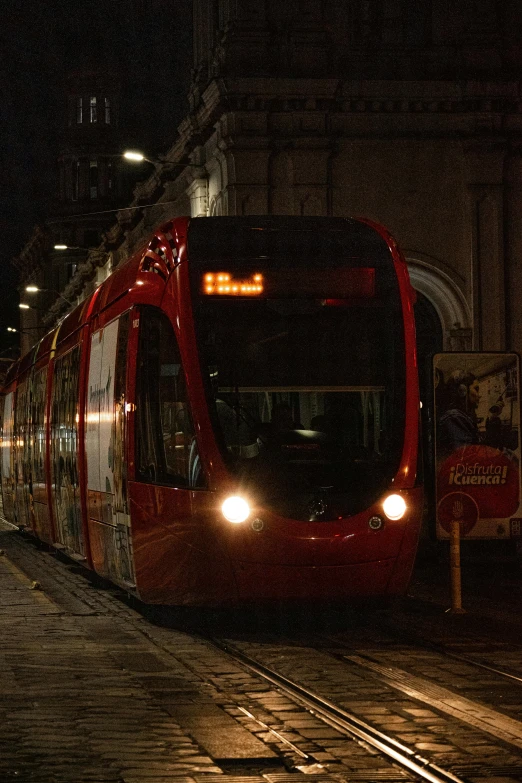 a red train coming up the tracks at night