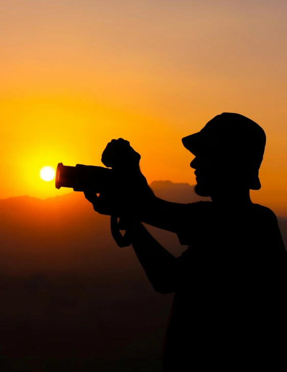 a person with a camera and a sunset