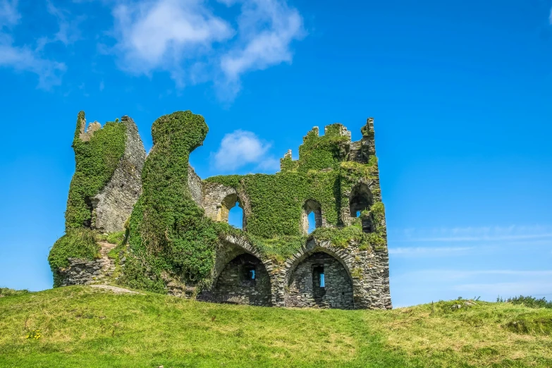 an old brick castle on top of a hill covered in ivy