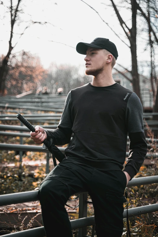 a man standing by some metal rail holding a pipe