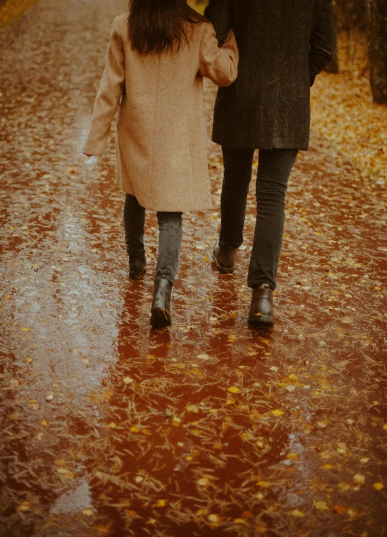 two people walking down a street holding an umbrella