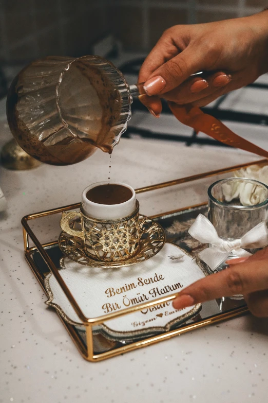 a person is pouring soing from a glass bowl onto a small tray