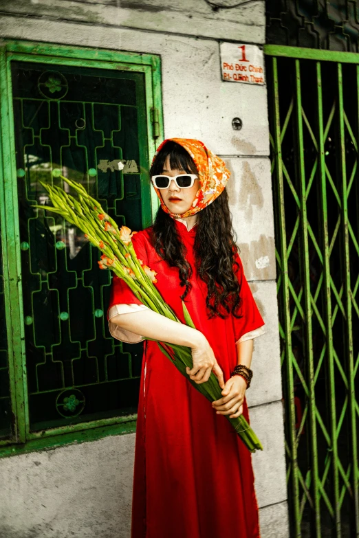 a woman with sunglasses holding a bunch of long green grass