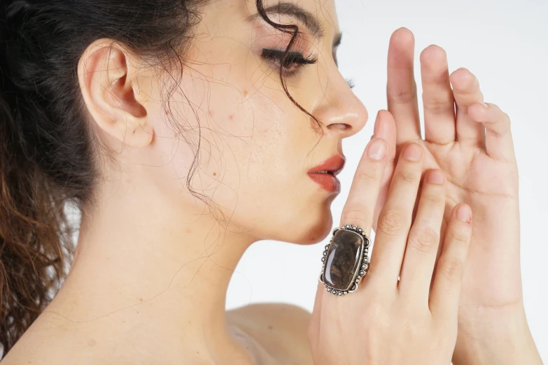 a woman holding her face up with a ring in her hands