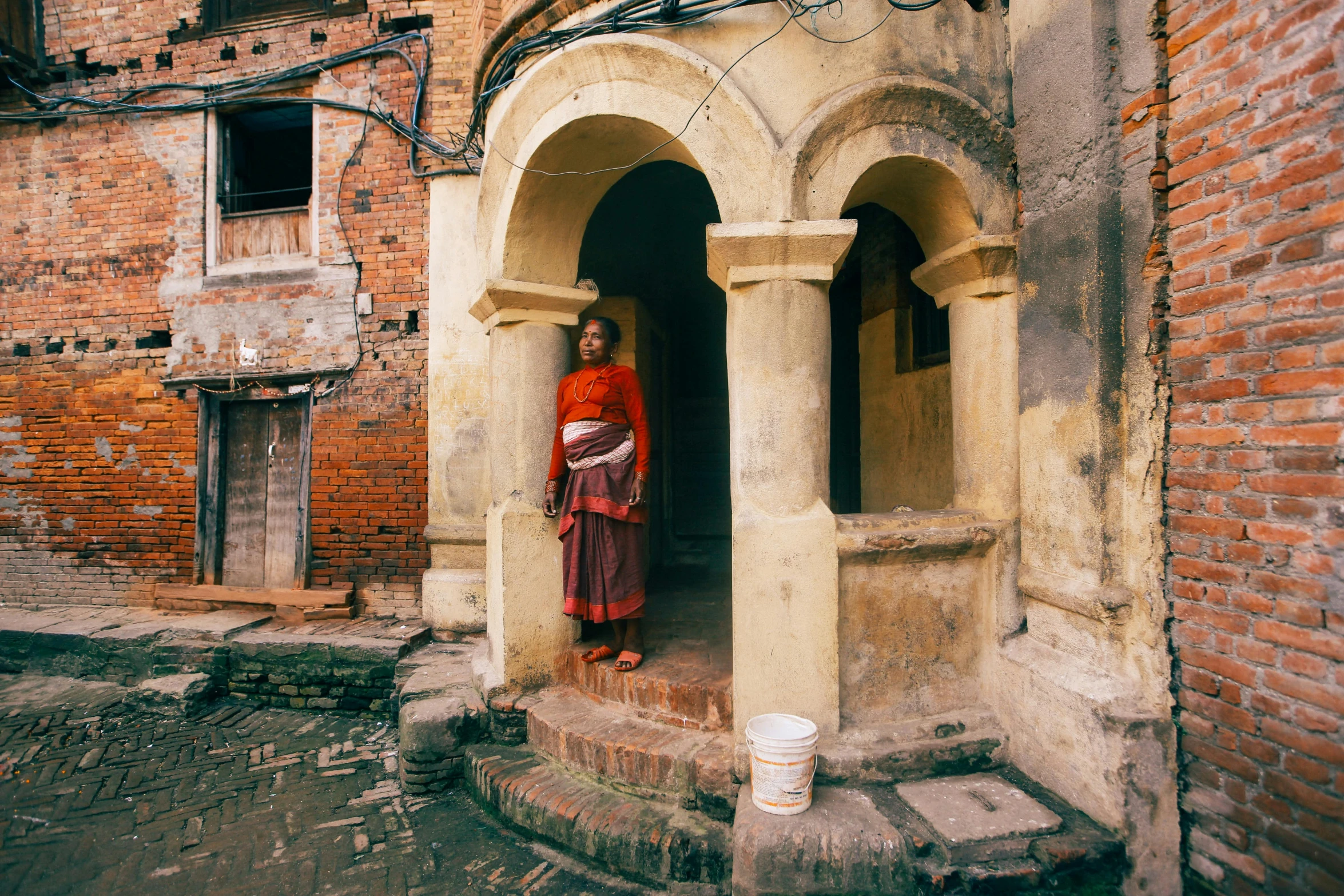 an asian woman stands in a small arched doorway