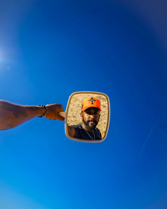 a man standing in front of a mirror under a blue sky