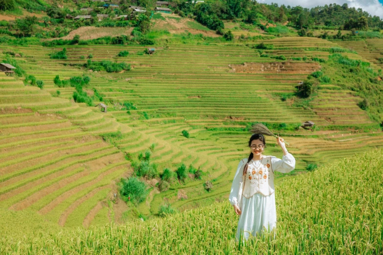 a woman in white dress standing on the side of a hill