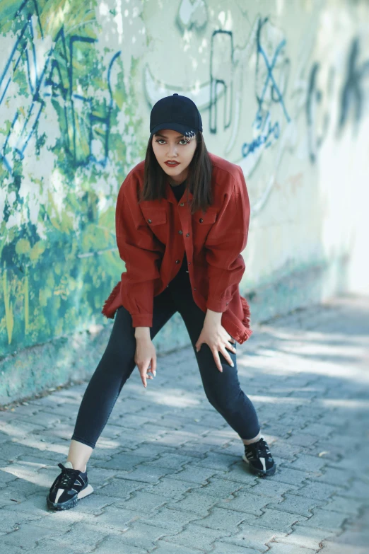 a young woman crouches on the ground by graffiti