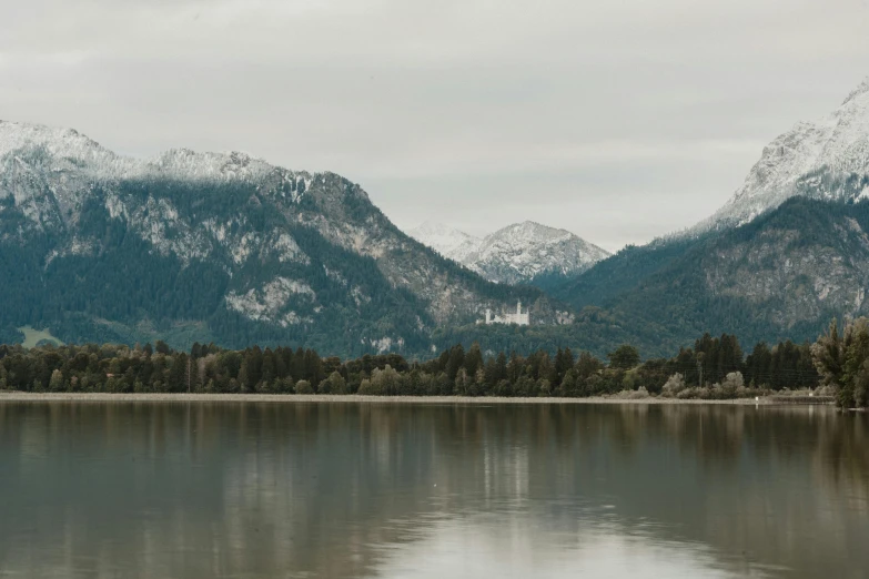 some mountains are covered with snow on the lake