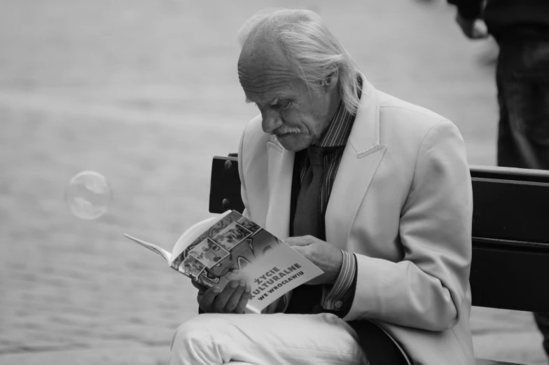 a man sitting on a bench blowing a bubble