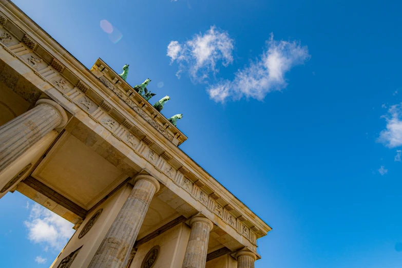 statues sitting atop a tall building under a cloudy blue sky