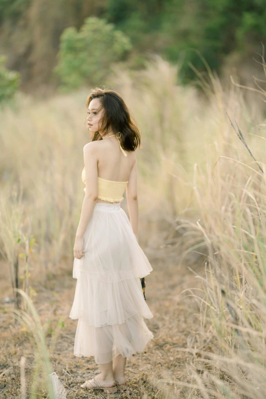 a young woman wearing a dress walking across a dirt field