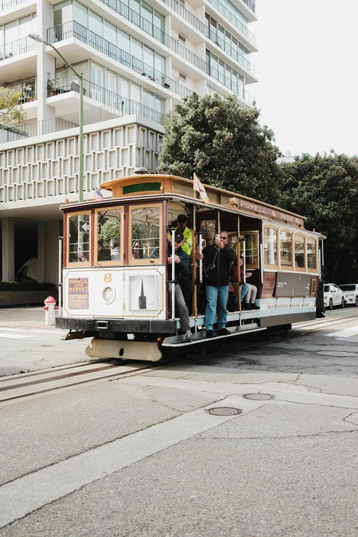 people stand inside a trolley car pulled by an old tram