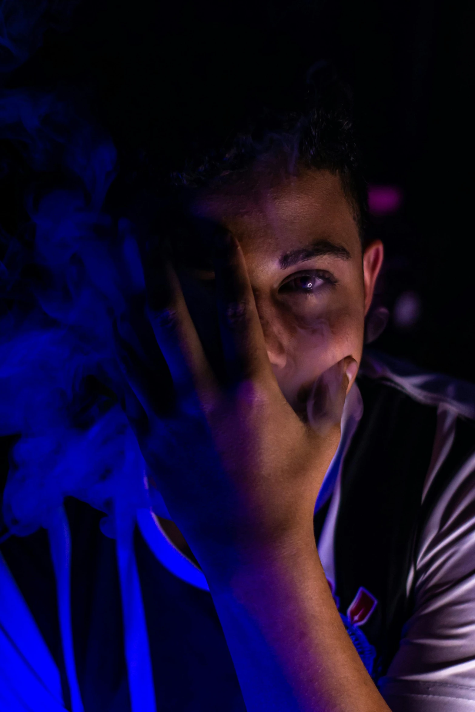 a man with his hand on a cell phone in a darkened room