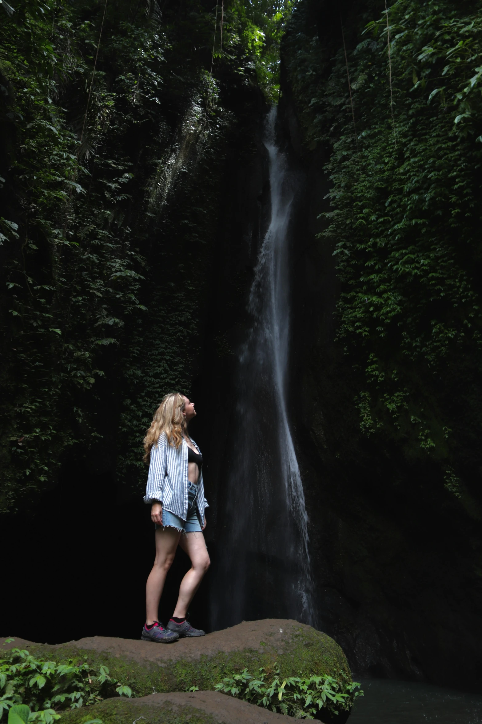 a person standing near a waterfall and a woman in boots