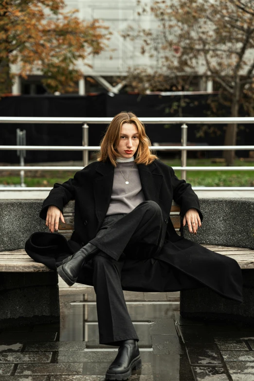 a woman sits on the bench in a park