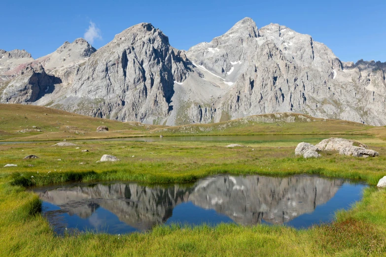 a reflection in the water with several large mountains behind it