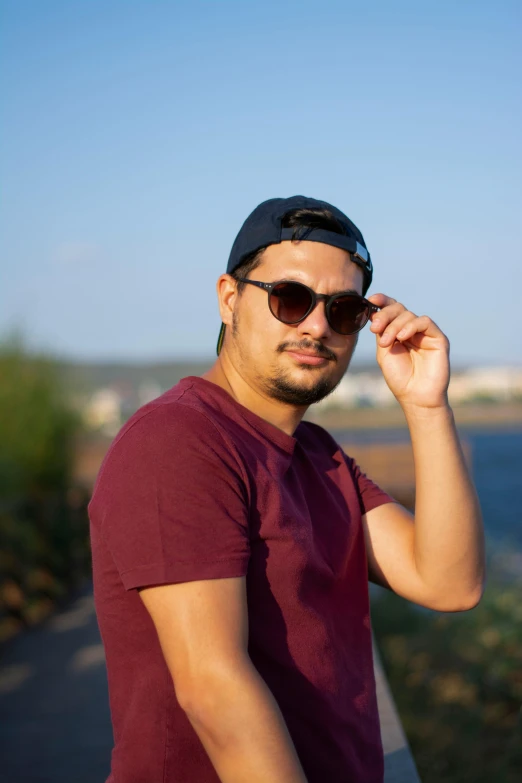 a man in maroon is posing by the water