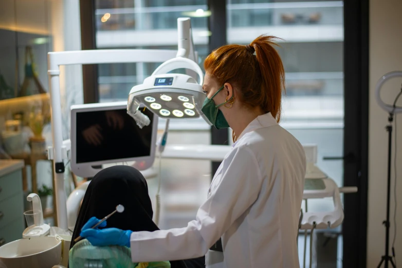 a dentist wearing medical supplies examining a person's teeth