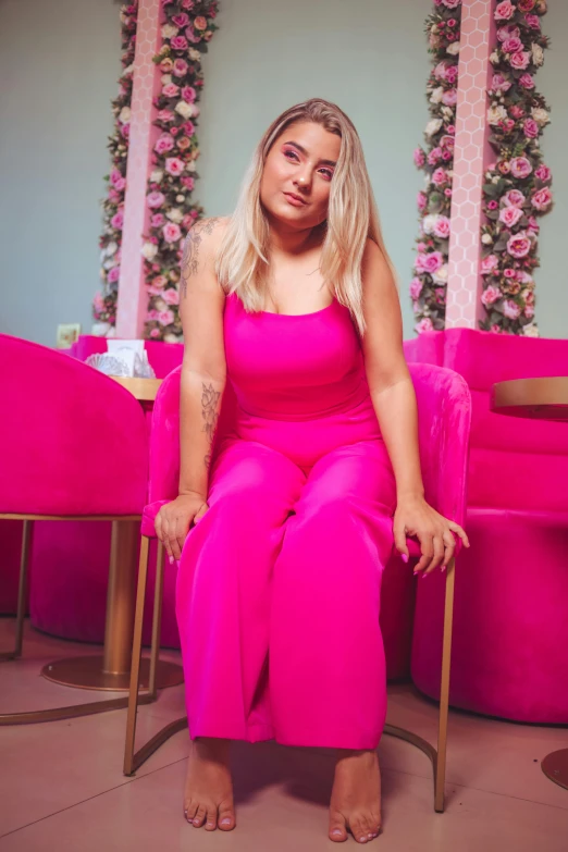 a woman wearing a bright pink jumpsuit and shoes in the background