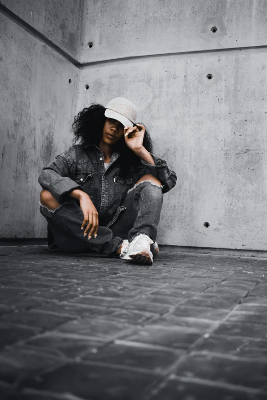 a woman with curly hair sitting on the ground with her legs crossed