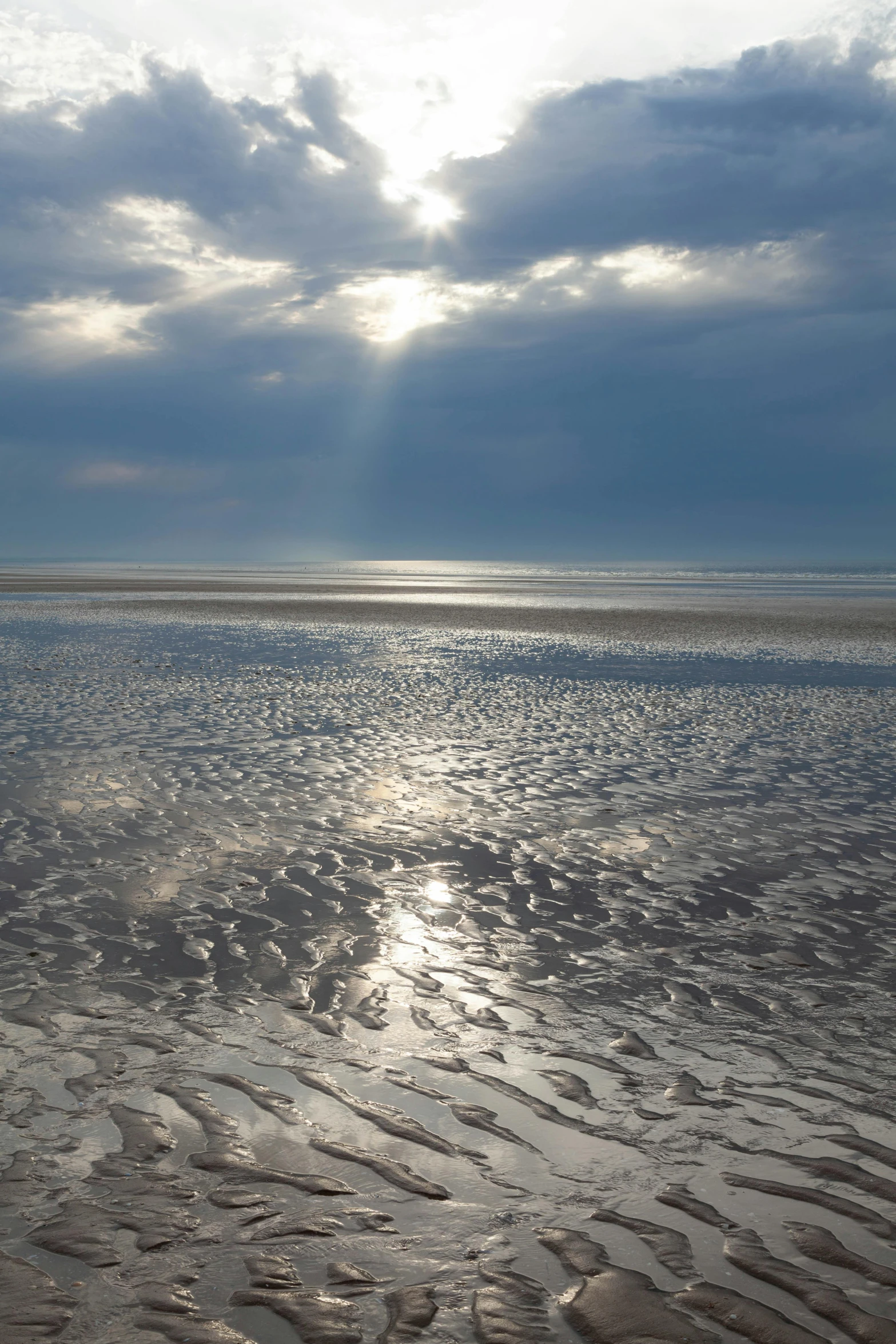 a sunset in the distance with a beach area and a lone boat