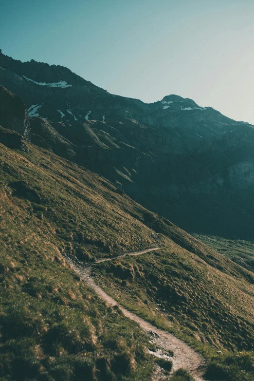 a dirt trail leads down a steep grassy mountain