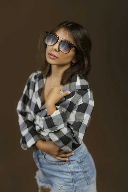 a girl wearing a plaid shirt with sunglasses