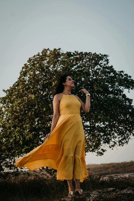 a woman is wearing a yellow dress and holding an umbrella