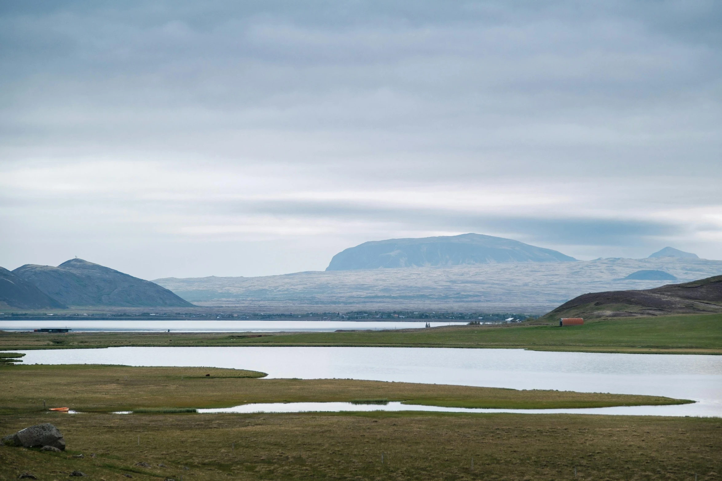 the horses are standing by a lake looking out at the mountains