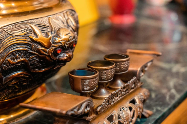 some gold cups on a table near a statue