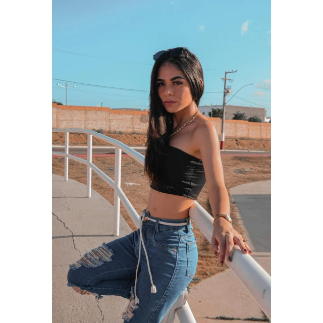 a young woman leaning on the rail wearing ripped jeans and black top